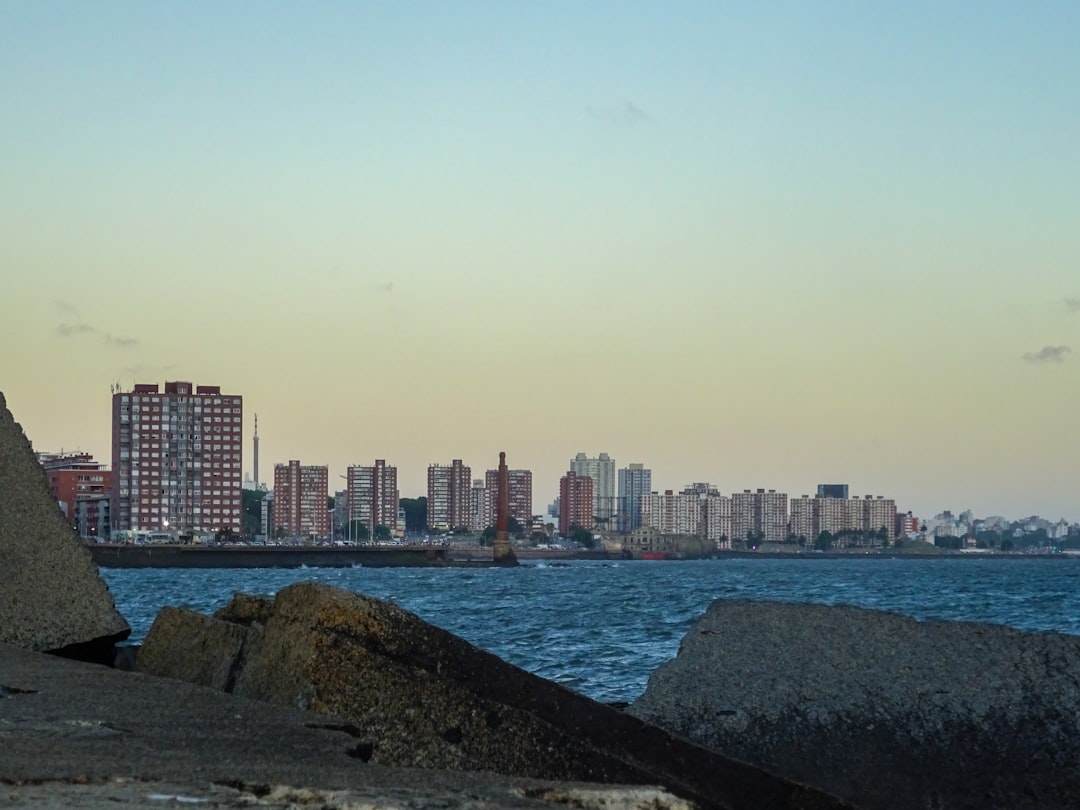 City skyline over water at dusk, with reflections of lights.